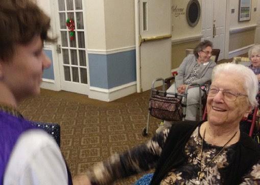 A young person sharing a joyful moment with an elderly care facility resident